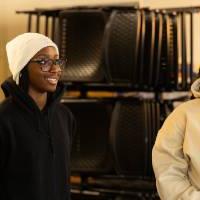 3 students smile while listening to speaker